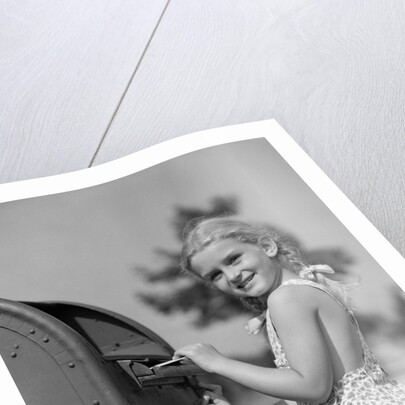 1930s 1940s child blond little girl with pigtails putting letter into mail box, looking at camera by Anonymous