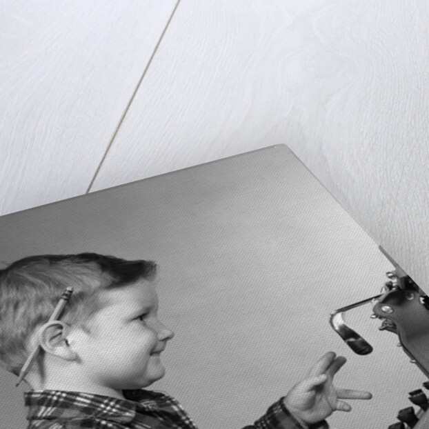 1950s smiling young boy typing on typewriter by Anonymous