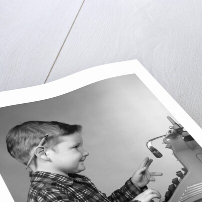 1950s smiling young boy typing on typewriter by Anonymous
