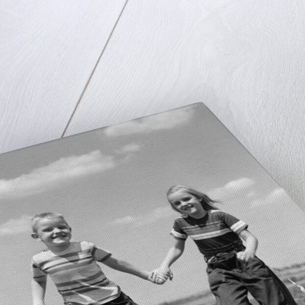 1950s boy girl running grassy farm field holding hands by Anonymous