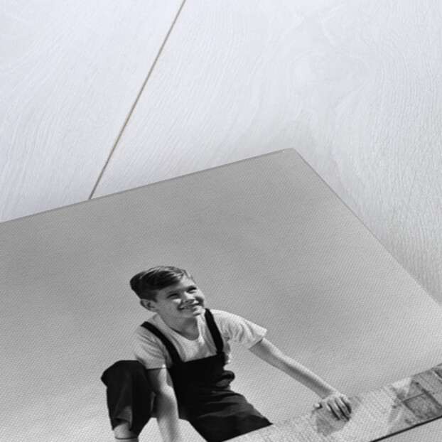 1940s brunette boy wearing overalls climbing over fence by Anonymous