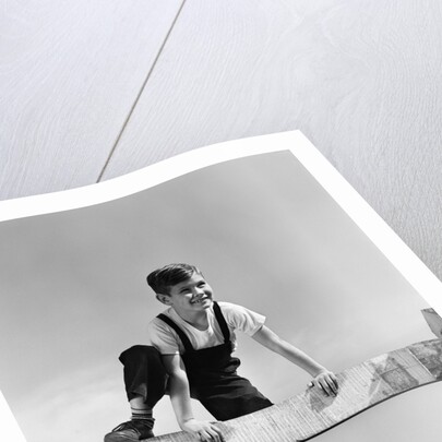 1940s brunette boy wearing overalls climbing over fence by Anonymous