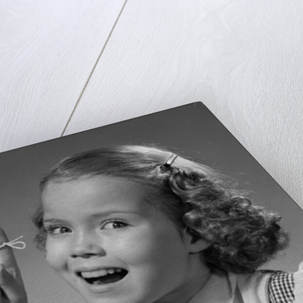 1950s little girl string tied on finger as reminder not to forget smiling looking at camera by Anonymous