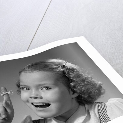 1950s little girl string tied on finger as reminder not to forget smiling looking at camera by Anonymous
