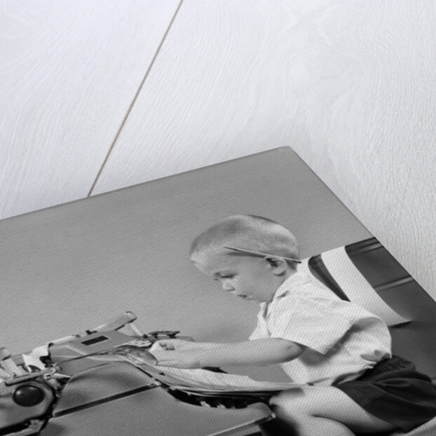 1950s child typing sitting at typewriter by Anonymous