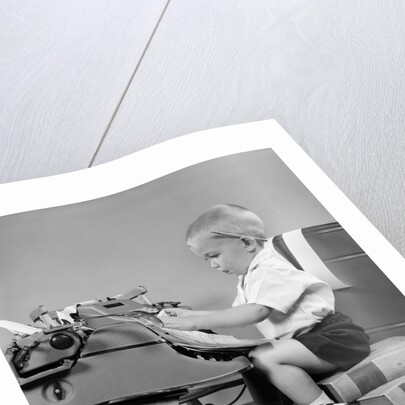 1950s child typing sitting at typewriter by Anonymous