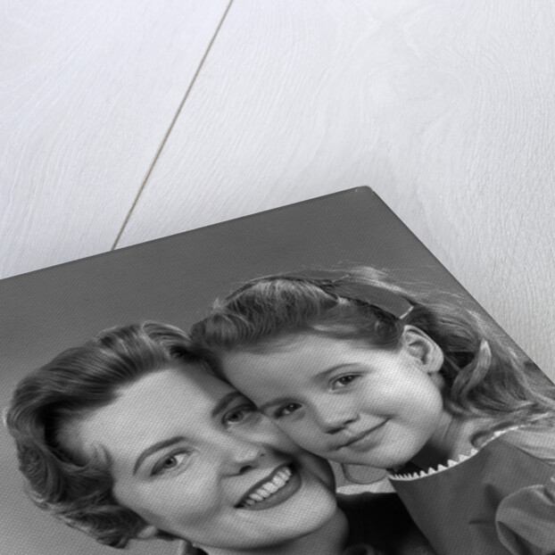 1950s girl daughter smiling hugging woman mother cheek to cheek together by Anonymous