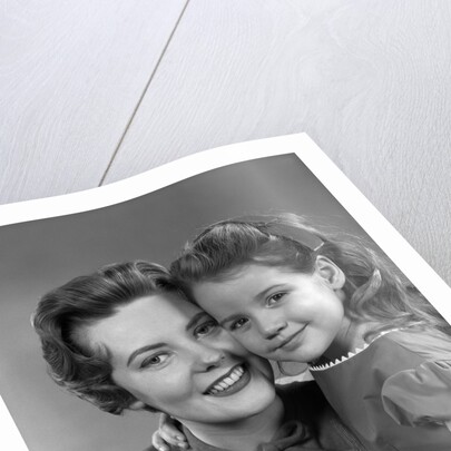 1950s girl daughter smiling hugging woman mother cheek to cheek together by Anonymous
