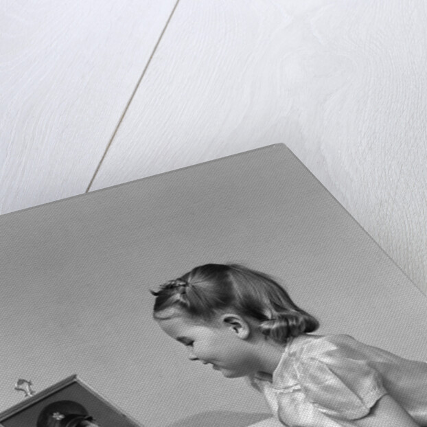 1940s child little girl looking at framed picture of her father a soldier in uniform by Anonymous