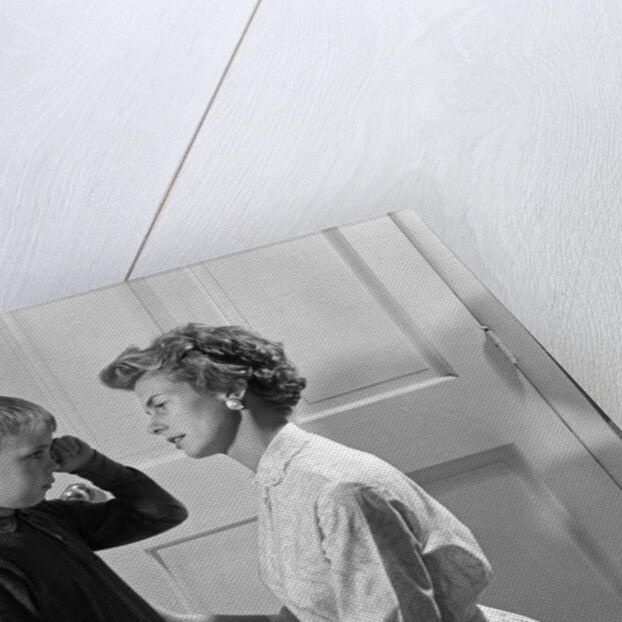 1960s sad crying boy rubbing his eyes is comforted or disciplined by his caring mother by Anonymous