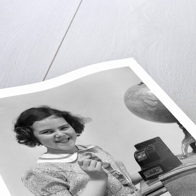 1930s child smiling girl putting money coin into toy cash register bank by Anonymous
