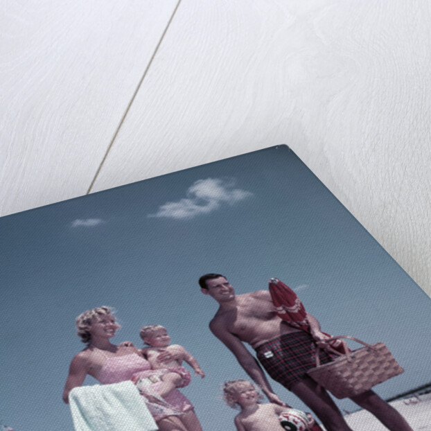 1950s family man woman mother father children boy girl son daughter standing sandy beach with toys and picnic basket by Anonymous