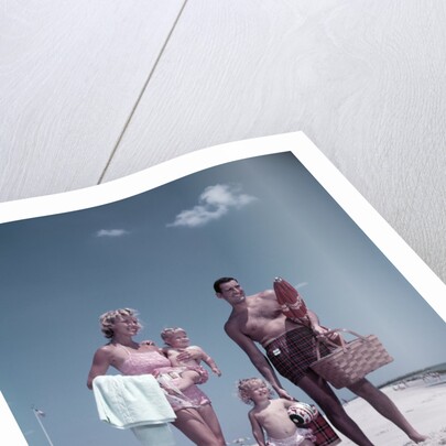 1950s family man woman mother father children boy girl son daughter standing sandy beach with toys and picnic basket by Anonymous