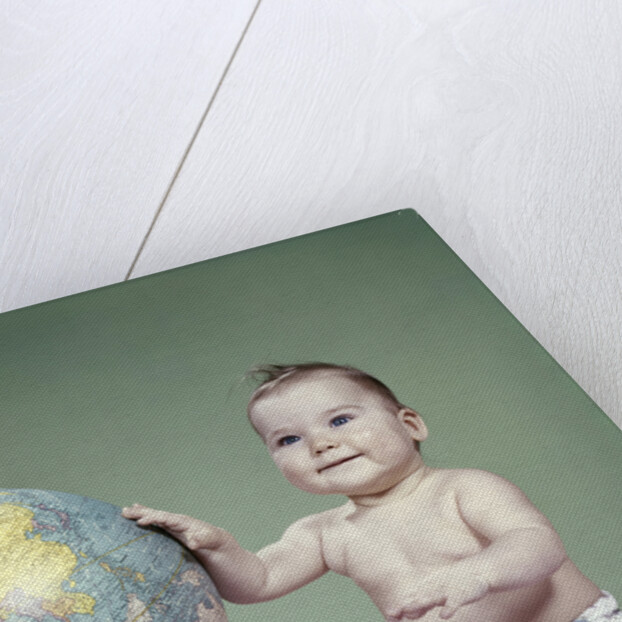 1960s smiling baby girl sitting in diapers hand touching world globe by Anonymous