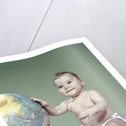 1960s smiling baby girl sitting in diapers hand touching world globe by Anonymous