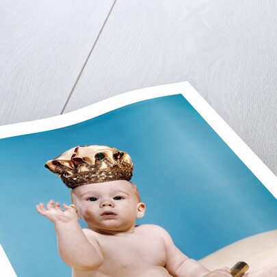 1960s baby wearing cloth diaper and crown holding a scepter waving with one arm raised looking at camera by Anonymous