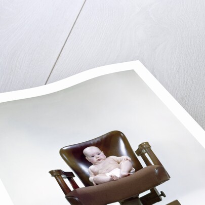 1960s chubby baby in diaper sitting in office executive chair by Anonymous