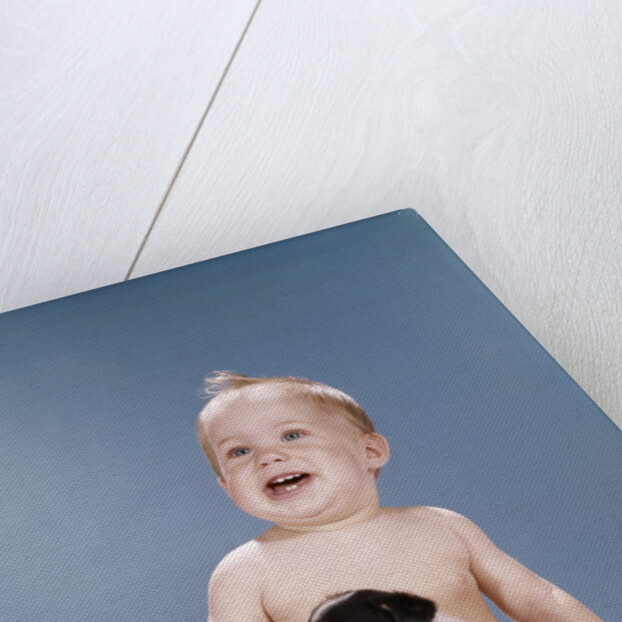 1960s smiling baby girl sitting in diapers playing with young black and white puppy dog by Anonymous