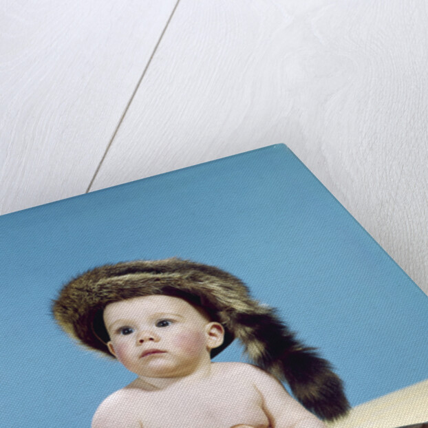 1960s baby boy wearing coonskin cap with stuffed animal and shotgun gun by Anonymous