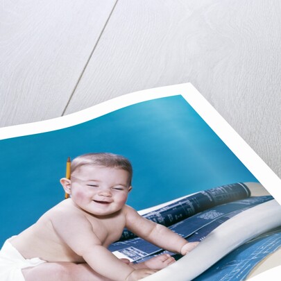 1960s baby eyes closed funny facial expression crawling on rolling out blueprints by Anonymous