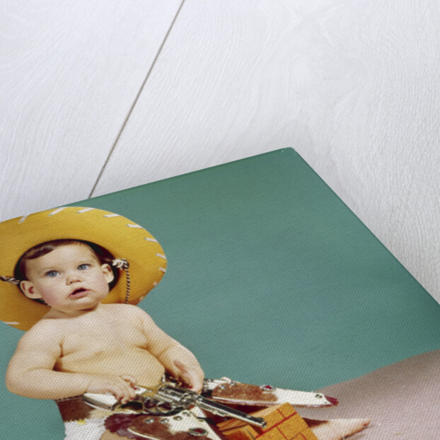 1960s baby wearing cowboy hat and holster with guns pistols looking at camera by Anonymous