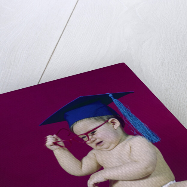 1960s graduate baby wearing mortarboard eyeglasses reading book by Anonymous