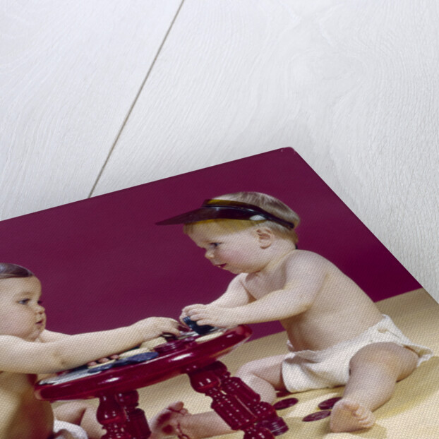 1960s two babies sitting at red stool playing cards poker with gambling chips by Anonymous