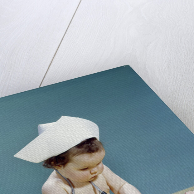 1960s baby wearing nurse nurse's cap stethoscope listening to doll heartbeat chest by Anonymous