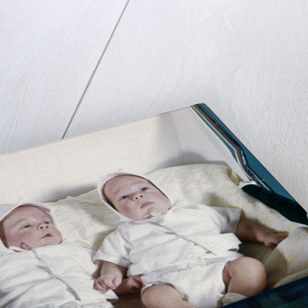 1950s 1960s twin boys dressed in white lying in stroller side by side by Anonymous
