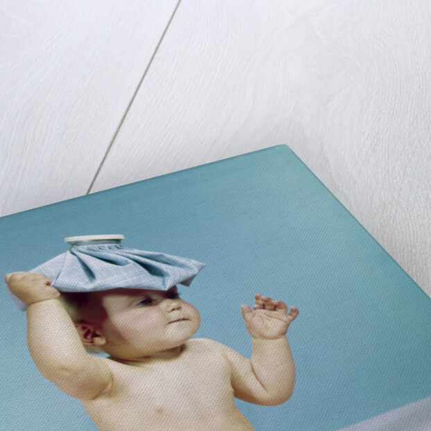 1960s baby sitting with ice pack on top of head by Anonymous