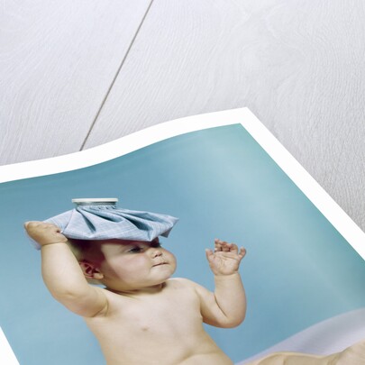 1960s baby sitting with ice pack on top of head by Anonymous