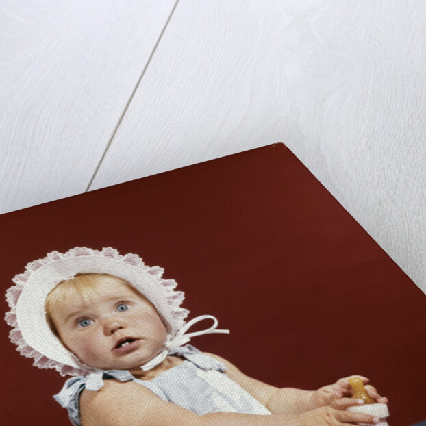 1960s baby girl ruffled bonnet holding bottle funny facial expression looking at camera by Anonymous