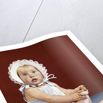 1960s baby girl ruffled bonnet holding bottle funny facial expression looking at camera by Anonymous