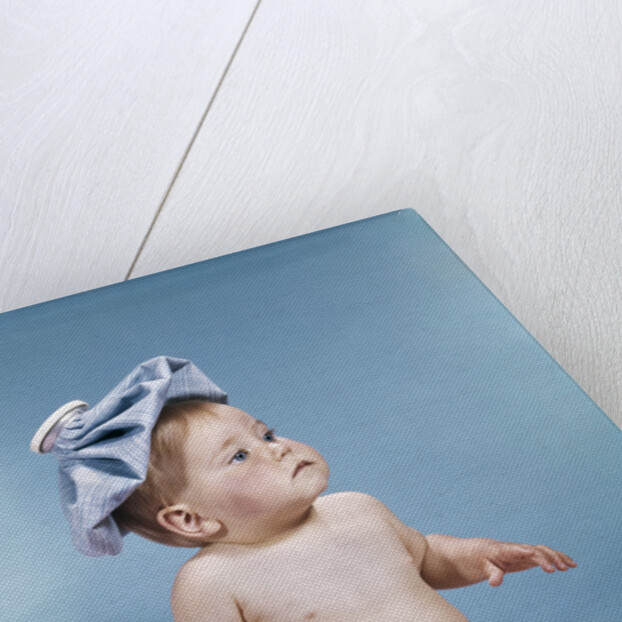 1960s baby sitting with ice pack on top of head by Anonymous
