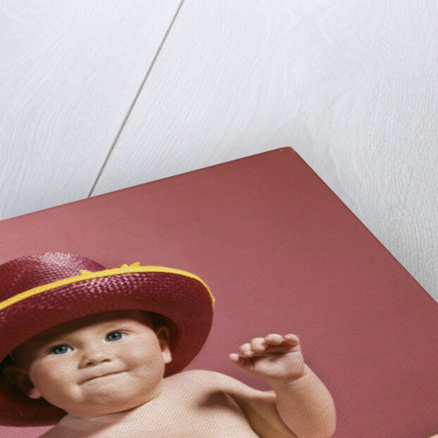 1960s baby making face wearing red straw hat by Anonymous