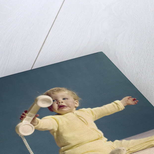 1960s baby holding telephone head set by Anonymous