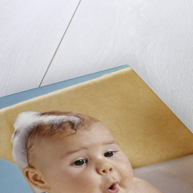 1960s baby with a surprised facial expression in bathtub covered with soap bubbles by Anonymous