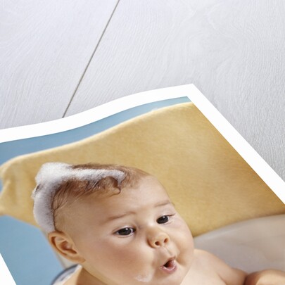 1960s baby with a surprised facial expression in bathtub covered with soap bubbles by Anonymous