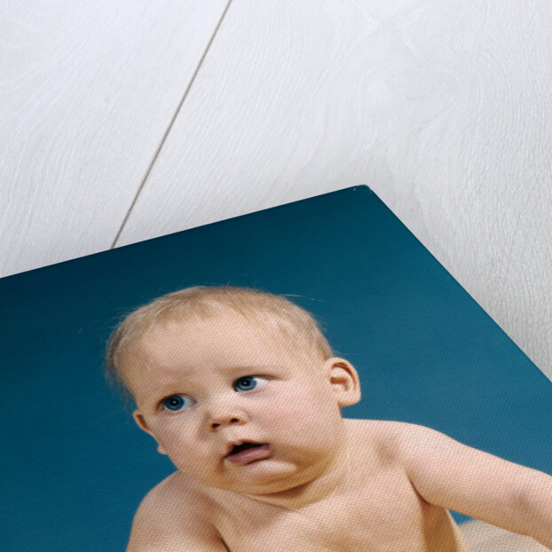 1960s baby big blue eyes raised up on arms looking to side by Anonymous