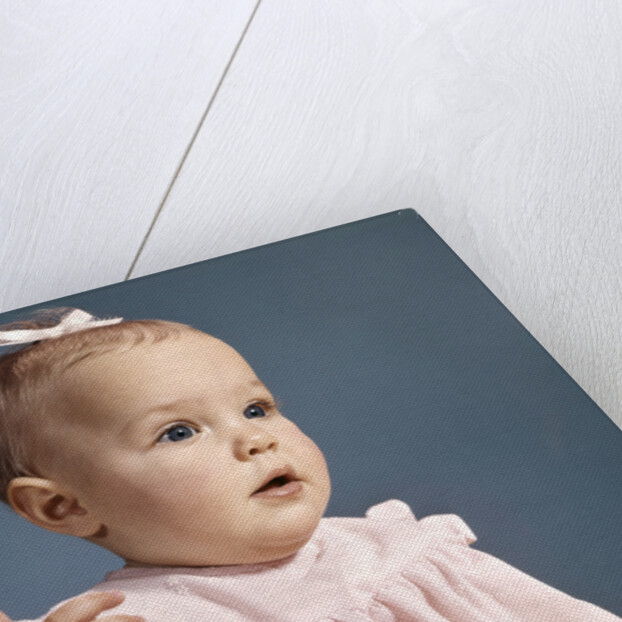 1960s baby girl wearing pink dress with a bow in her hair pointing a finger by Anonymous