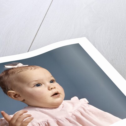 1960s baby girl wearing pink dress with a bow in her hair pointing a finger by Anonymous