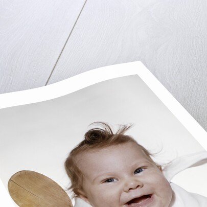 1960s 1970s smiling baby wearing bib and holding wooden spoon by Anonymous