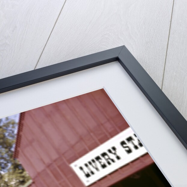 1960s cowboy sheriff with badge draws gun arrests gunfighter in front of livery stable by Anonymous