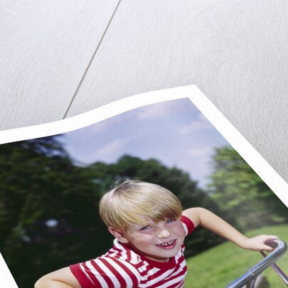 1970s 1960s smiling blond boy leaning over handlebars of bicycle looking at camera by Anonymous