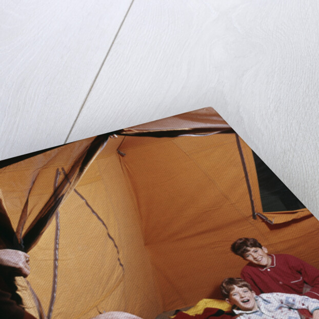 1960s father with lantern checking up on 3 boys in sleeping bags pajamas in tent by Anonymous
