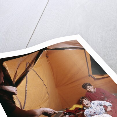1960s father with lantern checking up on 3 boys in sleeping bags pajamas in tent by Anonymous