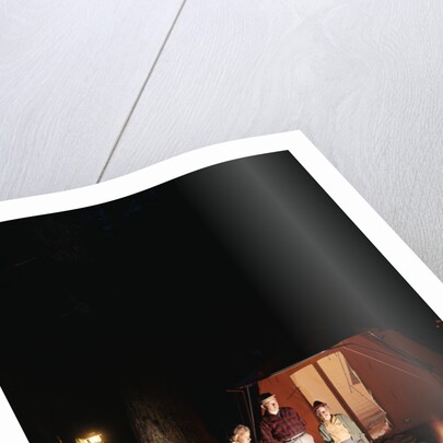 1960s night scene family gazing into campfire by tent by Anonymous