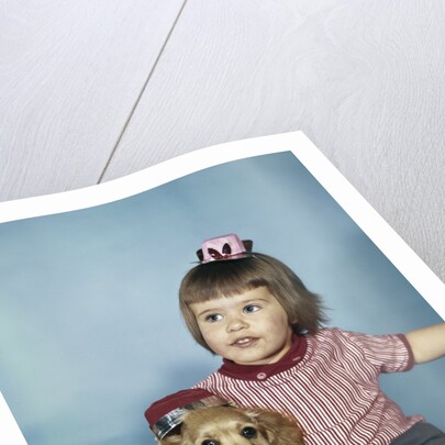 1950s 1960s little girl in party hat sitting holding a cocker spaniel puppy by Anonymous