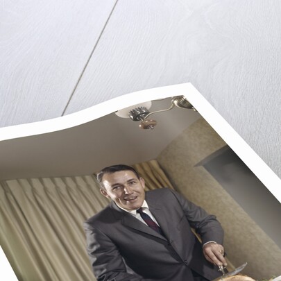 1960s man carving ham dinner looking at camera by Anonymous