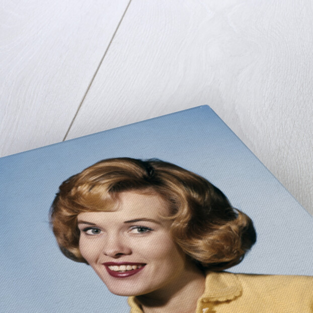 1960s smiling blond woman wearing a yellow sweater head tilted quizzical expression by Anonymous
